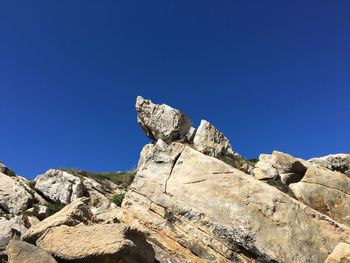 Low angle view of rock against clear blue sky