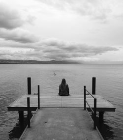 Empty pier on sea against cloudy sky