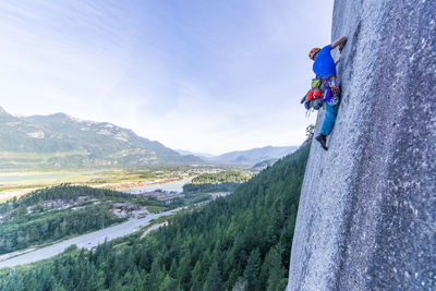 Man lead climbing granite squamish with background view of valley