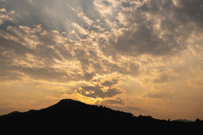 Low angle view of silhouette mountain against dramatic sky