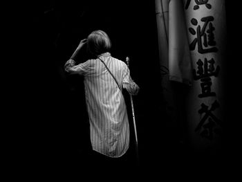 Rear view of woman standing in the dark