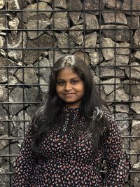 Portrait of young woman standing against wall