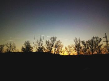 Silhouette of bare trees against sunset sky
