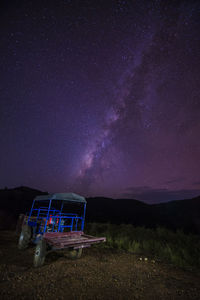 Tractor on field against sky at night