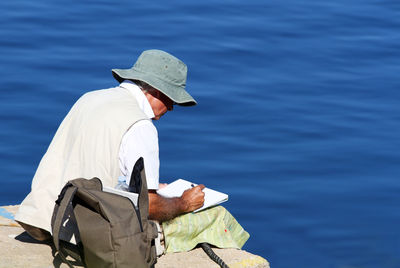 Man writing in book while sitting at beach