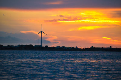 Silhouette of wind turbine against sky during sunset