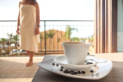 Coffee cup on table with woman in background