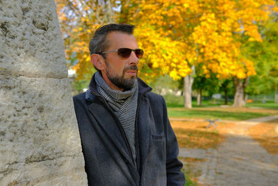 Portrait of young man wearing sunglasses standing against trees