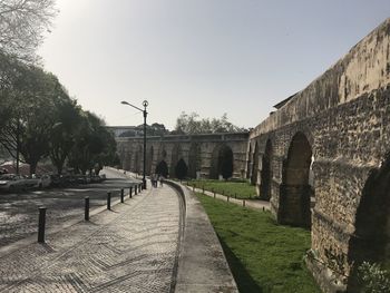 Empty footpath by buildings against clear sky