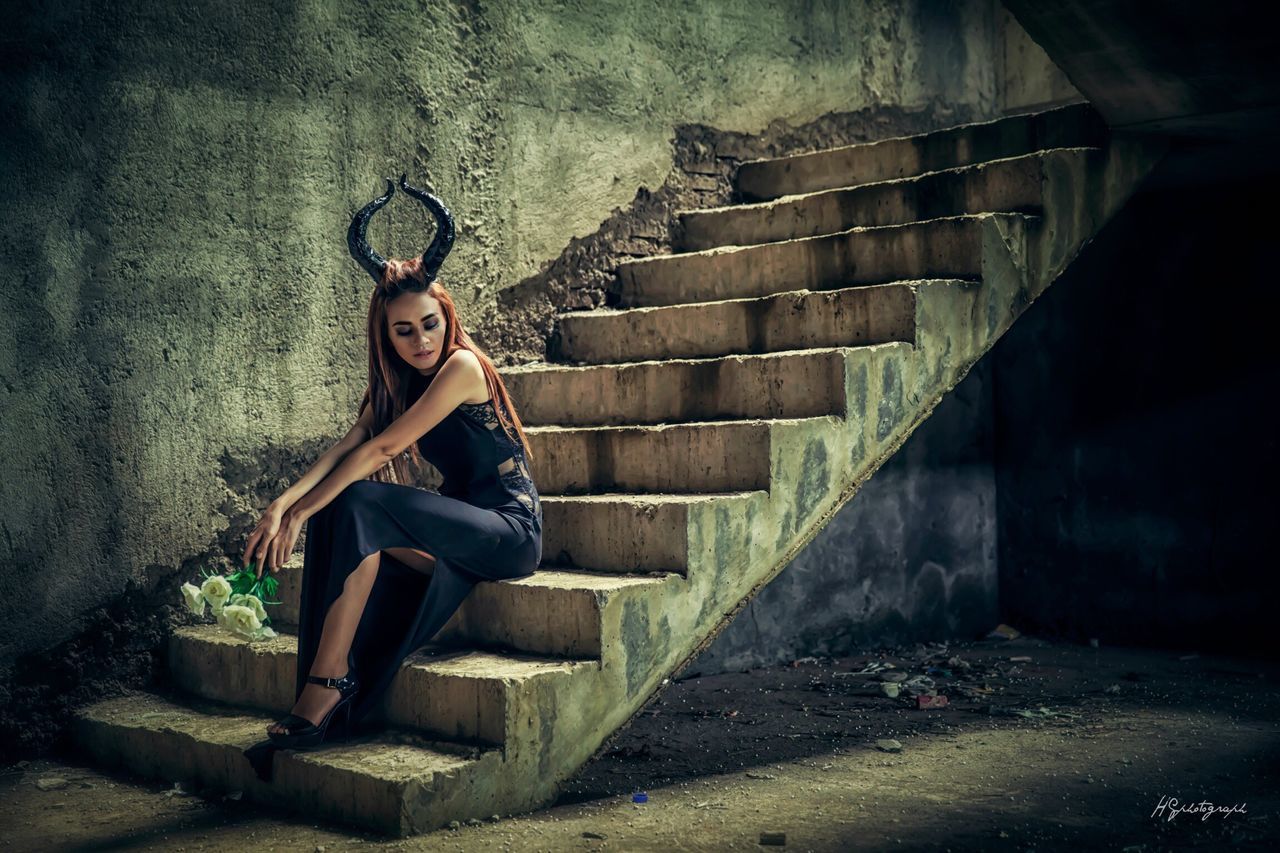 full length, lifestyles, sitting, steps, casual clothing, leisure activity, young adult, standing, built structure, abandoned, person, indoors, wall - building feature, architecture, relaxation, front view, looking at camera, portrait