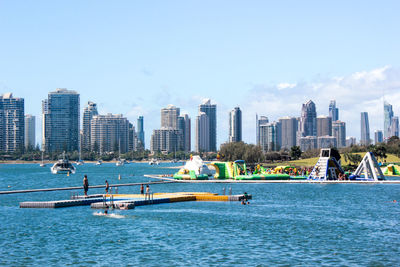 Boats in sea by cityscape against sky