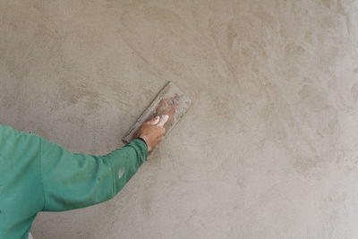 Cropped hand of worker applying cement on wall