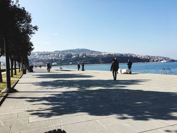 People on beach in city against clear sky