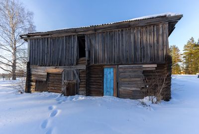 Abandoned house on field against clear sky during winter
