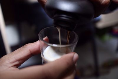 Cropped hand pouring drink in glass