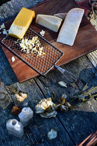 Blocks of smoked cheese and parmesan with vintage metal cheese grater on wood cutting board