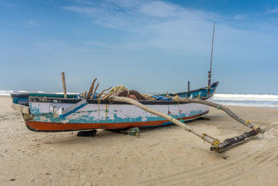 Boat moored on beach against sky