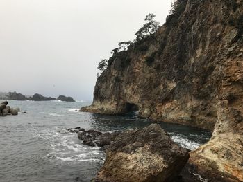 Rock formation by sea against clear sky