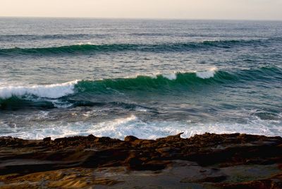 Waves flowing at sea against sky