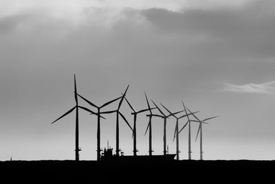 Windmills on land against sky