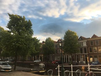 Cars on street by buildings in city against sky