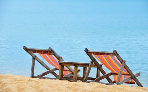 Empty chair on beach against blue sky