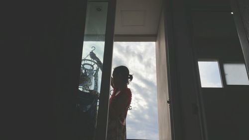 Man standing by window against sky