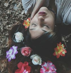 High angle view of woman wearing flowers lying down on field