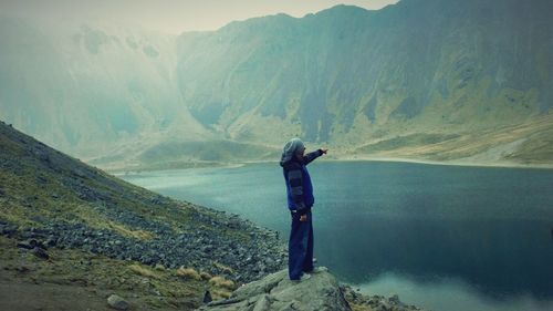 Rear view of woman standing on mountain against sky