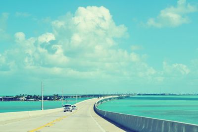 Vehicles on seven mile bridge over sea against sky