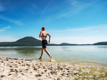 Shirtless fitness man exercise in training on the beach. muscular man is run in water along beach