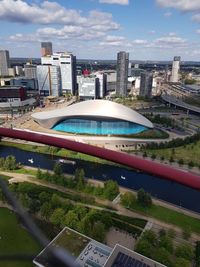 Aerial view of swimming pool by buildings in city against sky