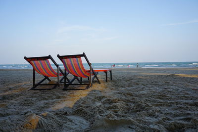 Chairs on beach against sky