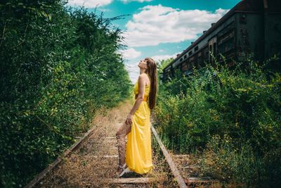 Woman standing by tree against plants