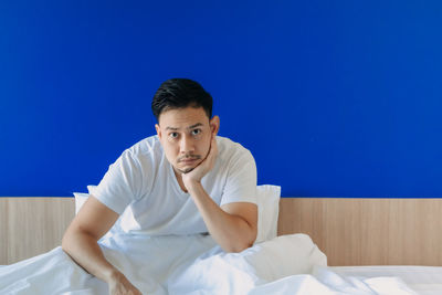 Portrait of young man sitting on bed