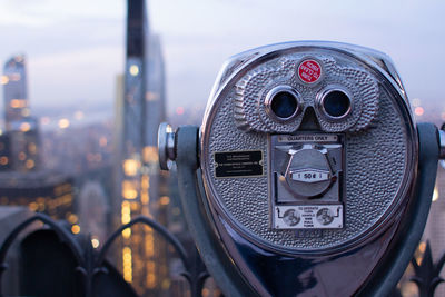 Close-up of coin-operated binoculars against cityscape