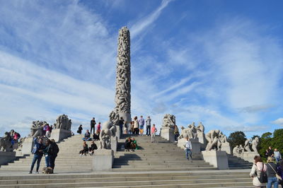 Low angle view of tourists against cloudy sky