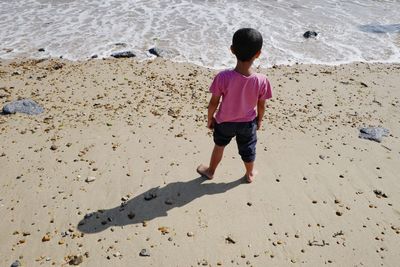 High angle view of boy standing on shore at beach