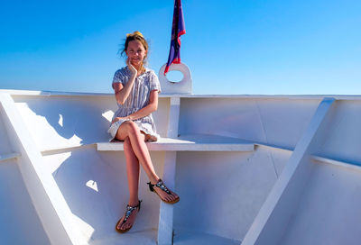 Portrait of woman sitting against blue sky