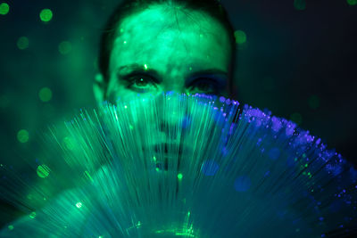 Close-up portrait of young woman against illuminated background