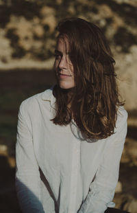 Young woman looking away while sitting outdoors