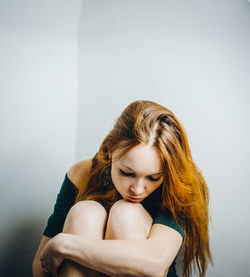 Portrait of young woman sitting against wall