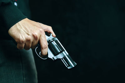 Close-up of man holding bottle against gray background