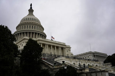 View of the senate capitol building during cloudy day, american flag half mast, washington dc, usa