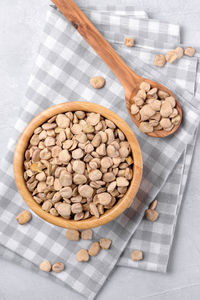 Cicerchia or indian pea in a wooden bowl and spoon with napkin on grey background, gluten free food