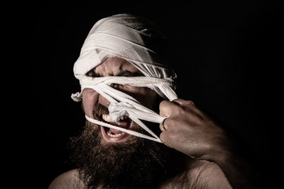 Close-up of man holding cigarette against black background