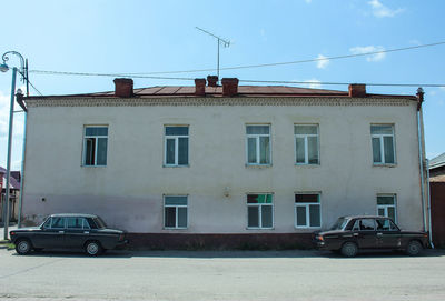 Residential building by road against sky