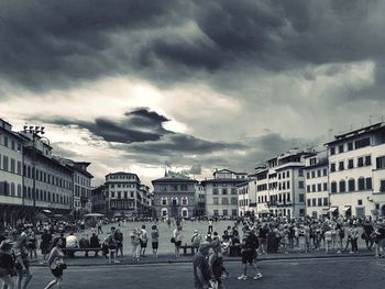 People at town square against cloudy sky