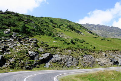 Scenic view of road by mountains against sky