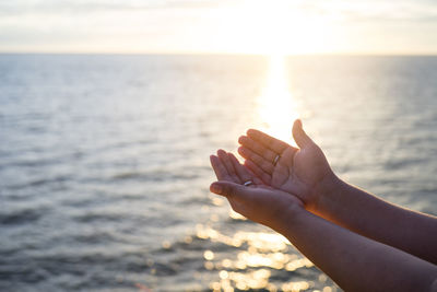 Cropped image of woman with cupped hands against sea